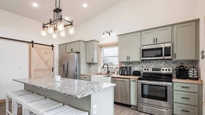 A modern kitchen with granite countertops, stainless steel appliances, and light green cabinetry. - Quiet Country Oasis with Hot Tub (Hardinsburg)