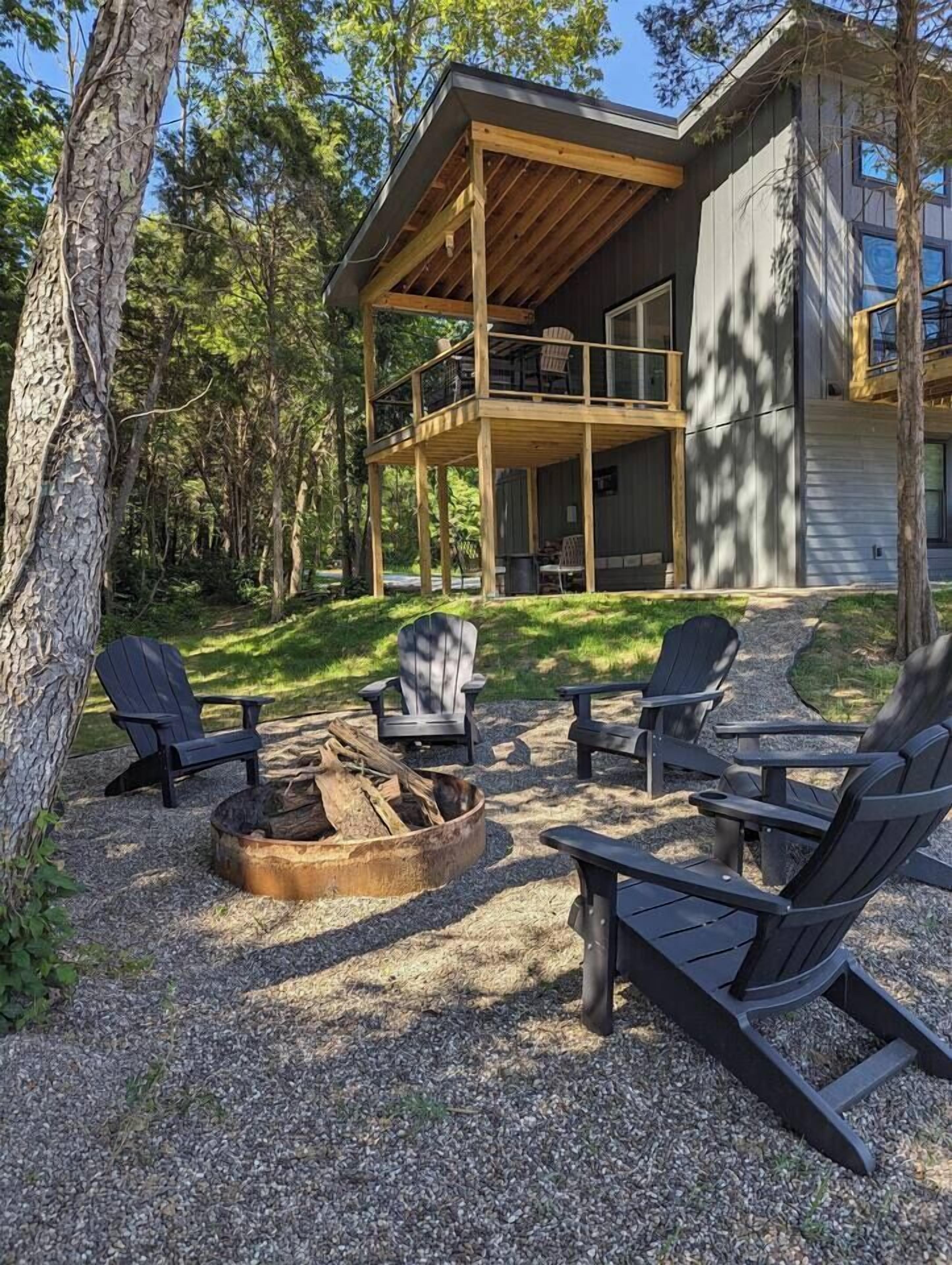 Une cabane dotée d’une terrasse, de meubles de jardin et d’un foyer extérieur.