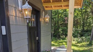 A covered porch with two potted plants and two wall-mounted lights. - Quiet Country Oasis with Hot Tub (Hardinsburg)