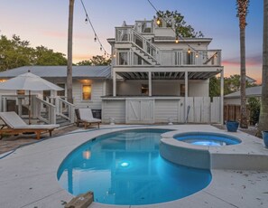 A two-story house with a swimming pool and a hot tub.