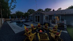 Ein Garten mit Swimmingpool, Sitzgelegenheiten im Freien und einer Feuerstelle.