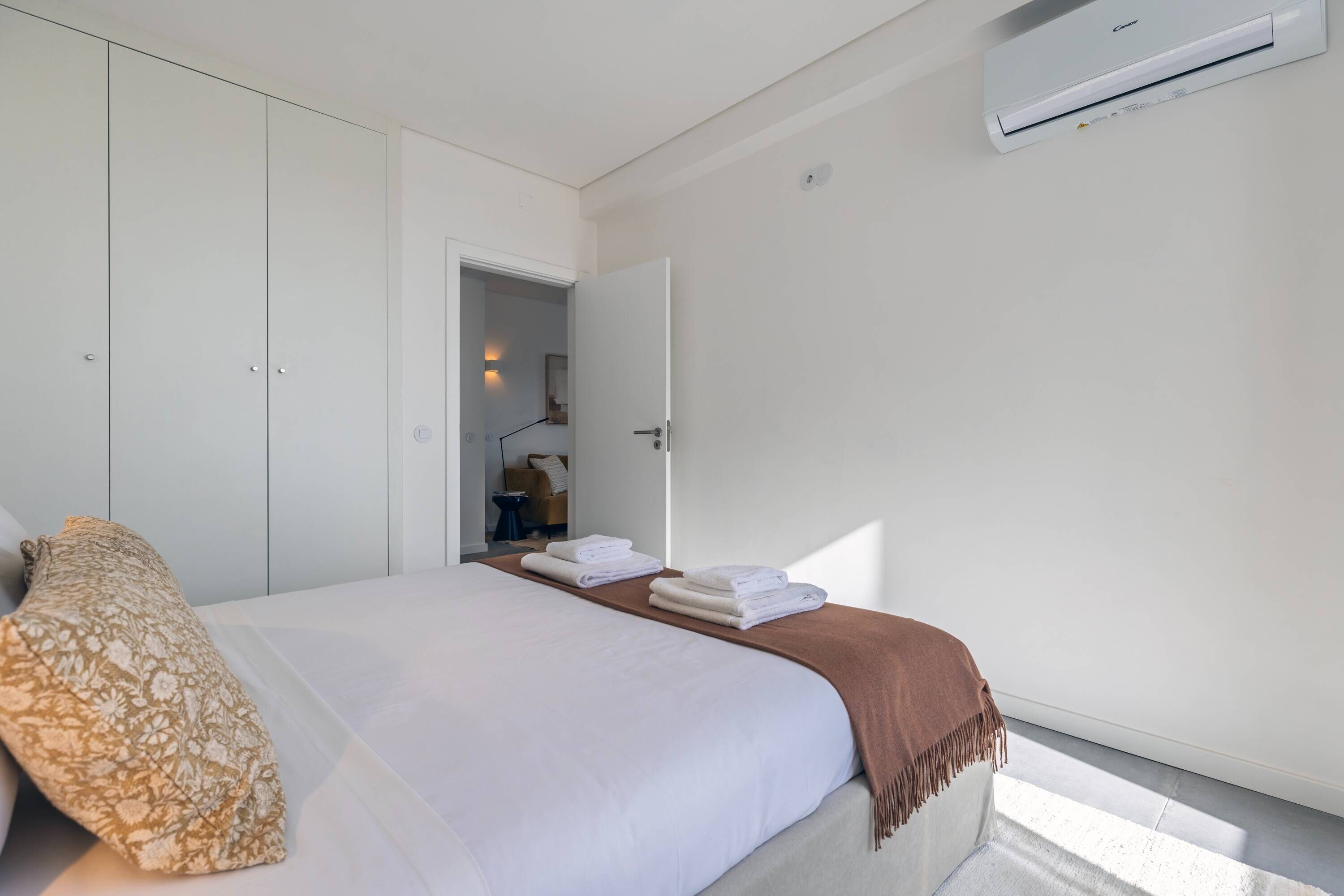 Un dormitorio con cama, armario y aire acondicionado.