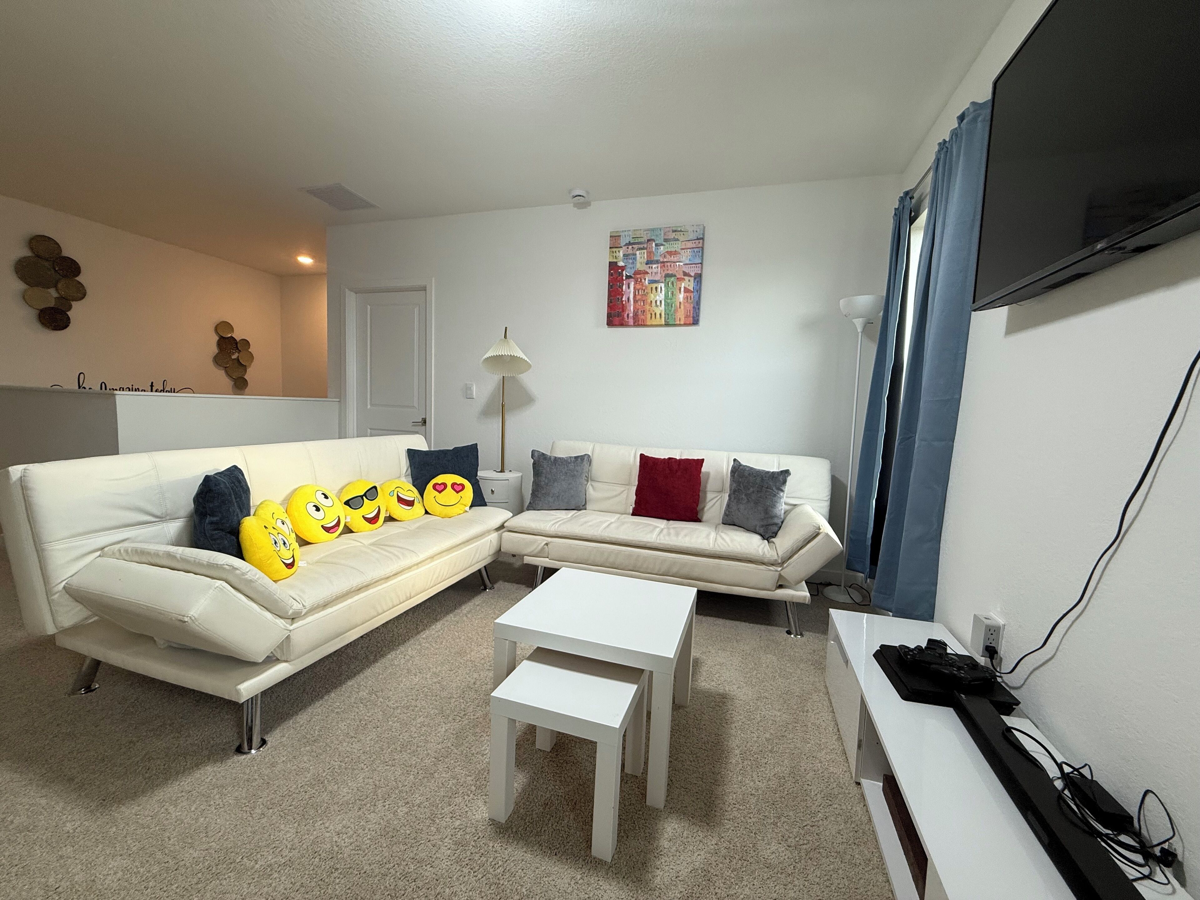 Una sala de estar con un sofá blanco, una mesa de centro y un televisor sobre un mueble.