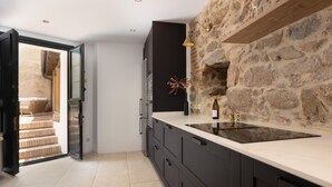 A modern kitchen with dark cabinetry, a stone accent wall, and a large island with a black countertop.