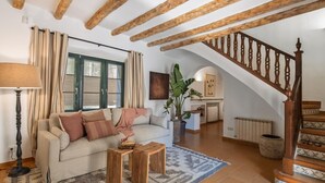 A cozy living room with a sofa, coffee table, and a staircase leading to an upper level.
