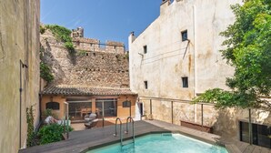 A pool area with a stone wall and a wooden deck.