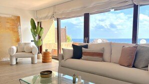 A modern living room with a white sofa, a glass coffee table, and a view of the sea. - DÚPLEX FRENTE AL MAR, PISCINA PANORÁMICA, DOS PKG (Tossa de Mar)