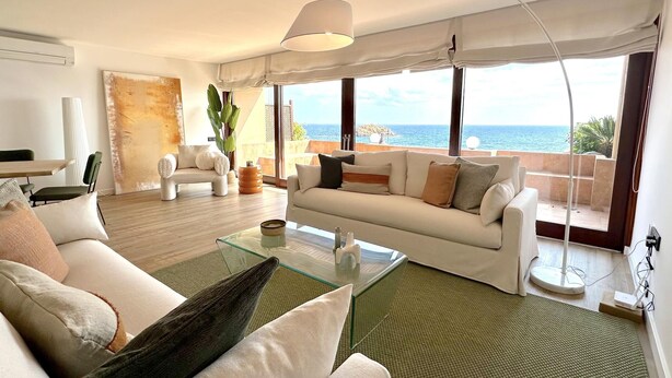 A modern living room with a glass coffee table, a white sofa, and a large window offering a view of the sea. - DÚPLEX FRENTE AL MAR, PISCINA PANORÁMICA, DOS PKG (Tossa de Mar)