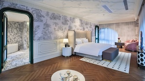 A modern hotel room with a large bed, a sitting area, and a view of the city.