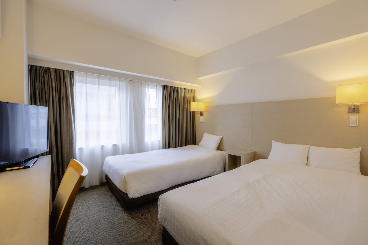 Ein Hotelzimmer mit zwei Betten, einem Fernseher und einem Schreibtisch.