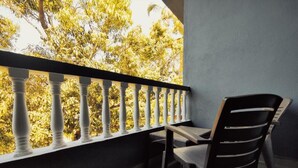 Een balkon met uitzicht op bomen, een stoel en een tafel.