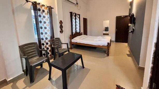 Een slaapkamer met een bed, een bureau, twee stoelen, een plafondventilator en een wandairconditioner.