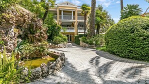 A hotel with a paved pathway, a rock garden, and a well-maintained hedge. - Saint Laurent Apt Garden View, Menton, France (Menton)