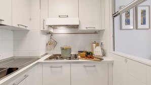 A modern kitchen with white cabinets, a stainless steel sink, and a countertop with a pot, vegetables, and a knife. - Saint Laurent Apt Garden View, Menton, France (Menton)