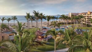 Un complexe hôtelier doté d’une piscine, de palmiers et offrant une vue sur la plage.