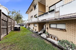 A residential building with a small courtyard, a wooden fence, and potted plants.