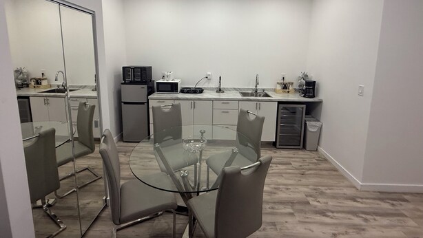 A compact kitchen with a glass dining table, modern appliances, and a minimalist design.