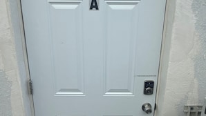A white door with a keypad lock and a push-in door code sign.