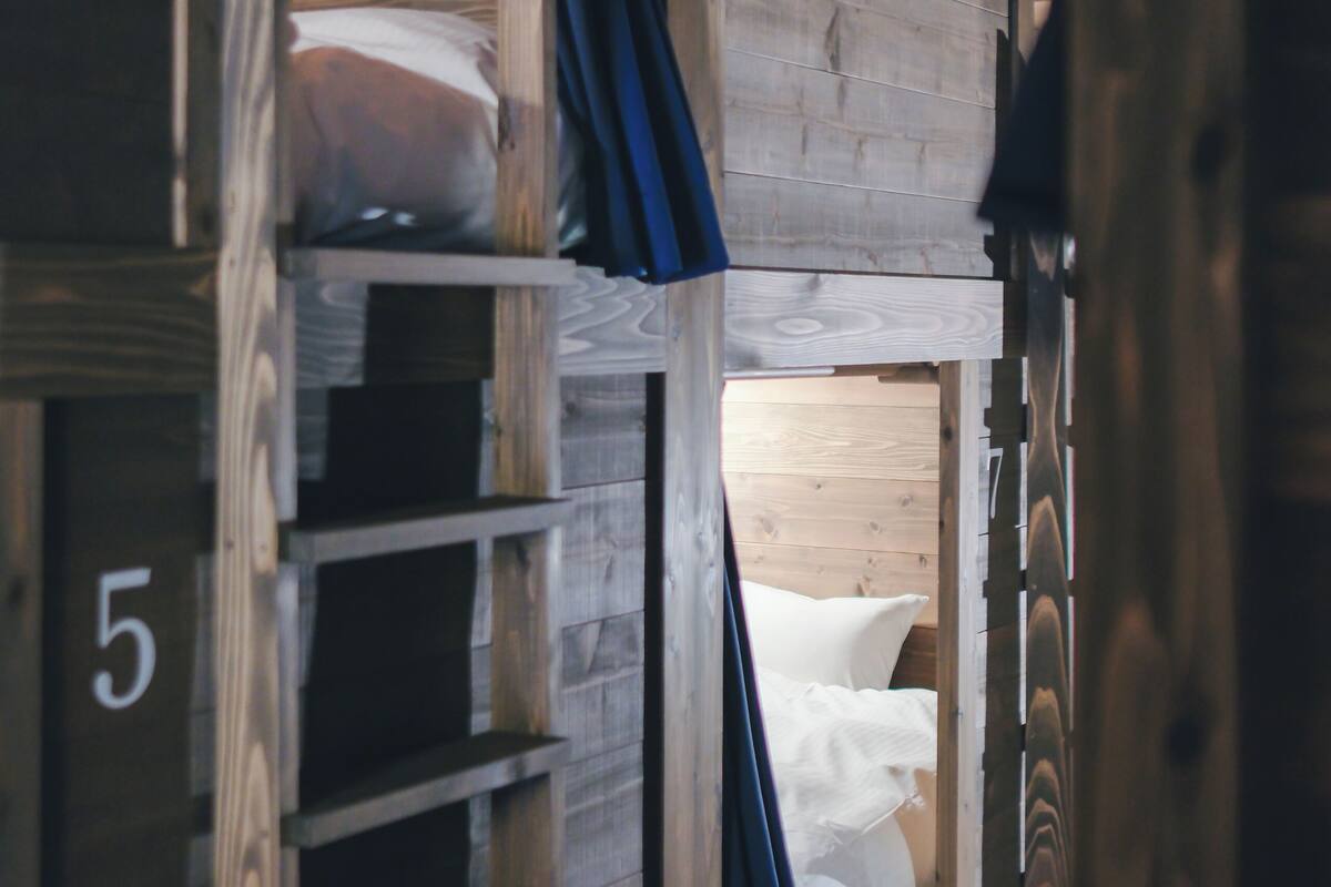 Une chambre avec des lits superposés, des murs en bois et un numéro affiché sur le côté gauche.