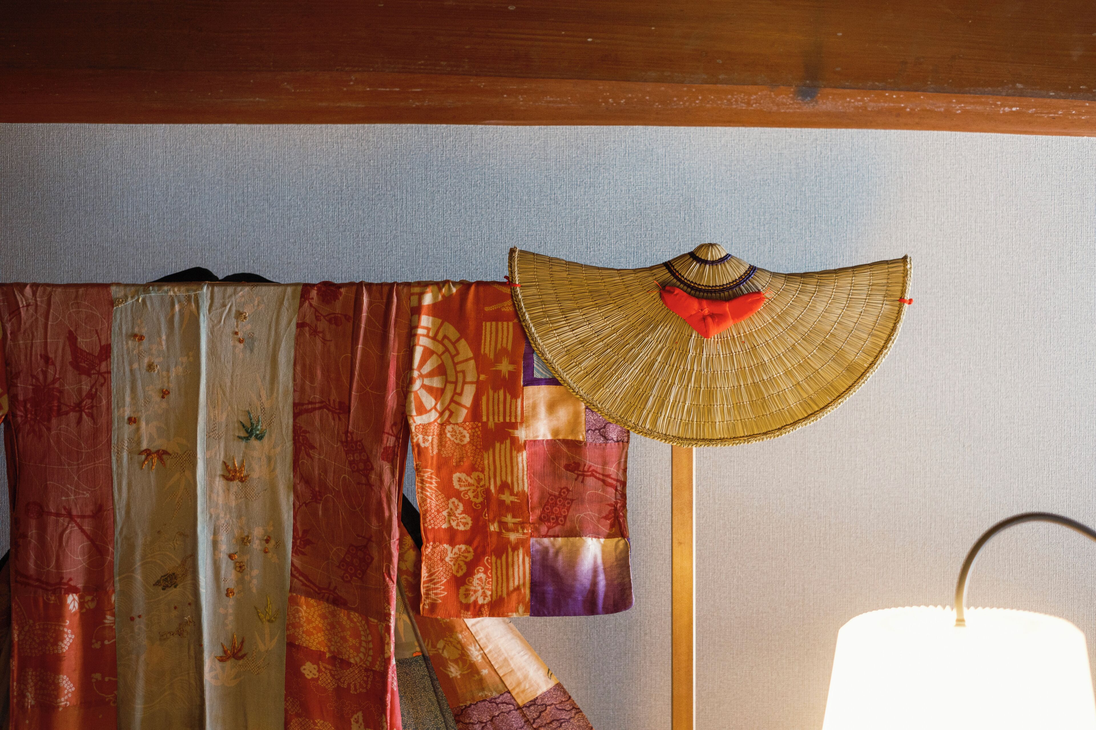 Una habitación con un abanico tejido tradicional, una lámpara y una cortina con estampado floral.