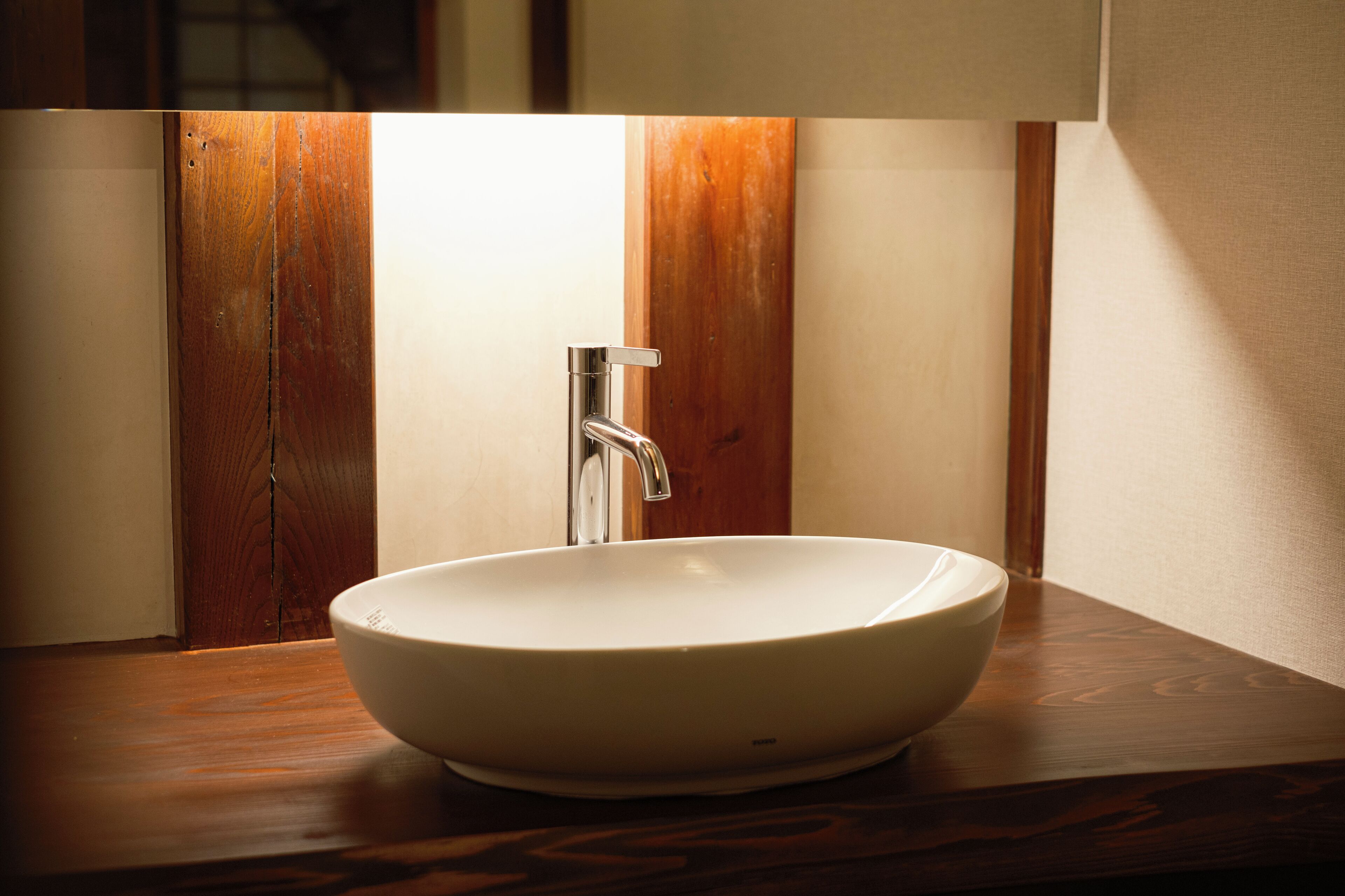 A white ceramic sink with a modern faucet on a wooden countertop.