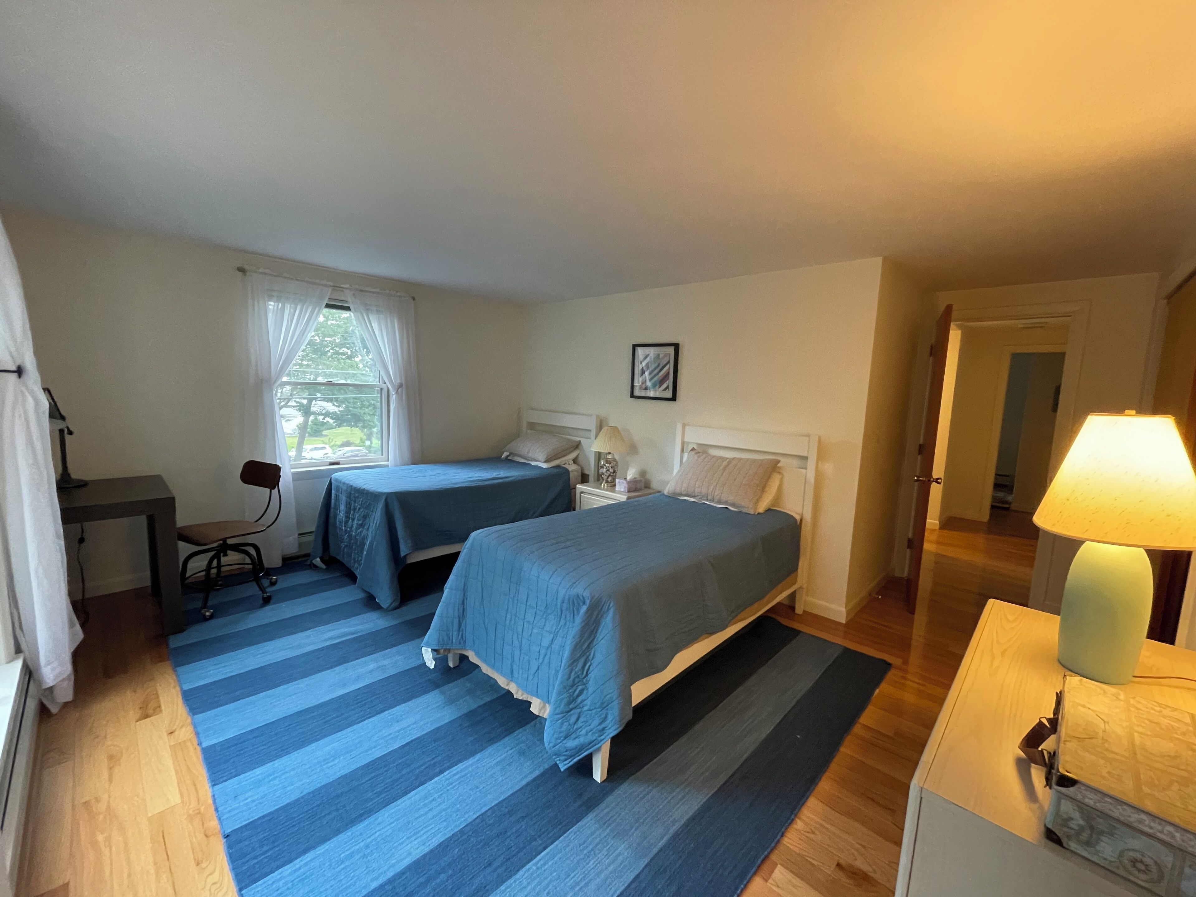 A bedroom with two beds, a desk, and a chair.
