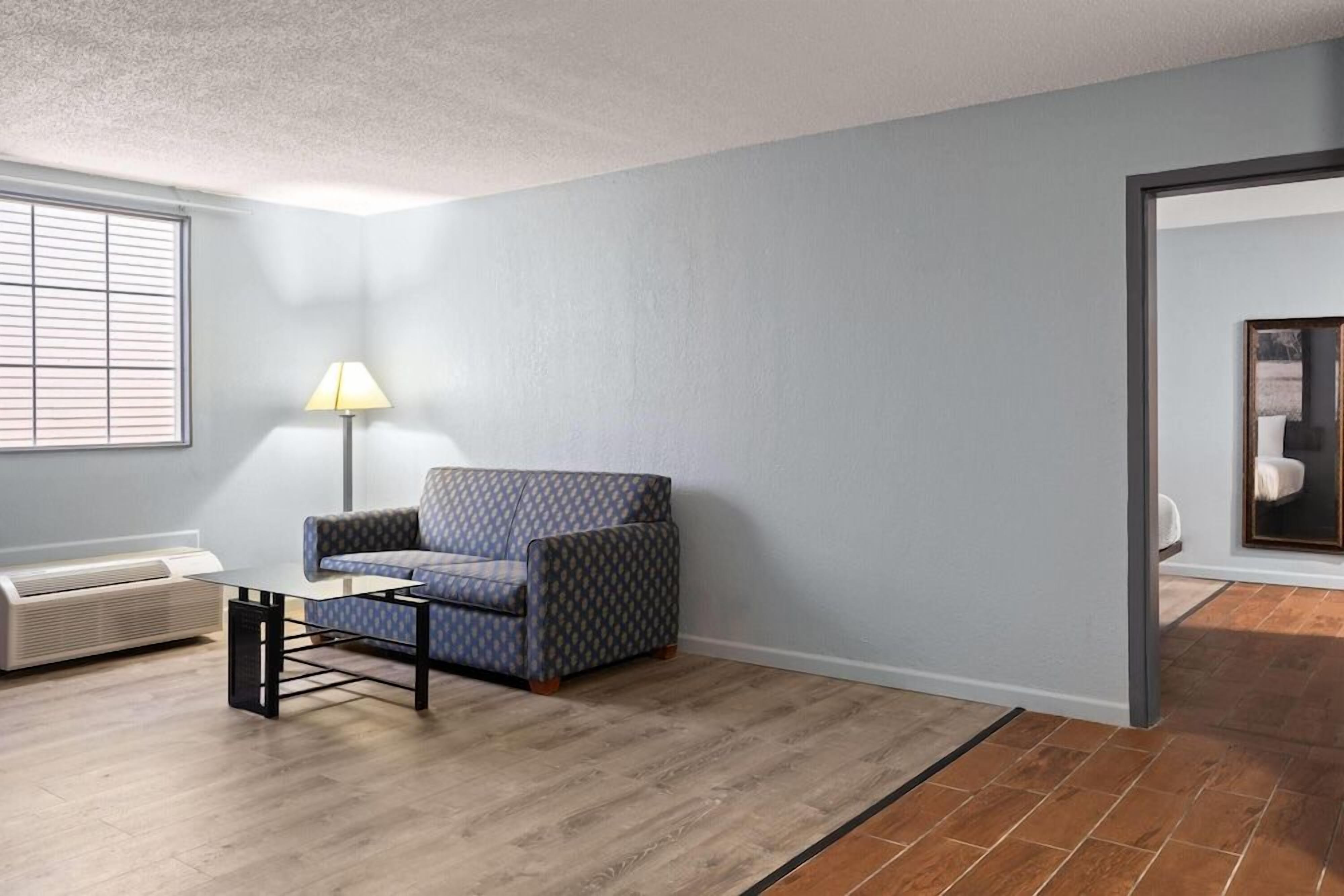 A room with a patterned sofa, a standing lamp, and a radiator.