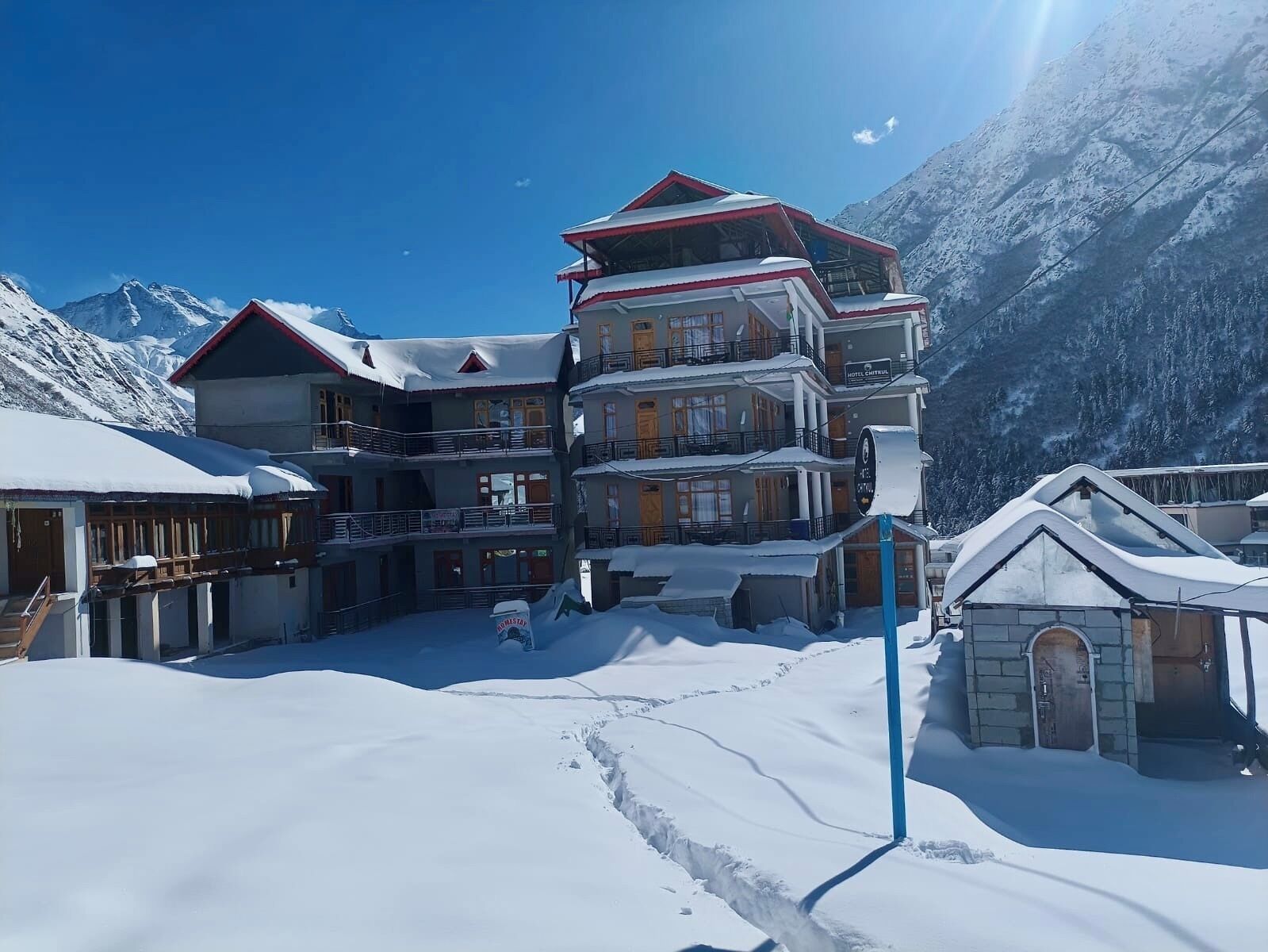 A multi-story hotel with balconies, snow-covered surroundings, and mountainous background.