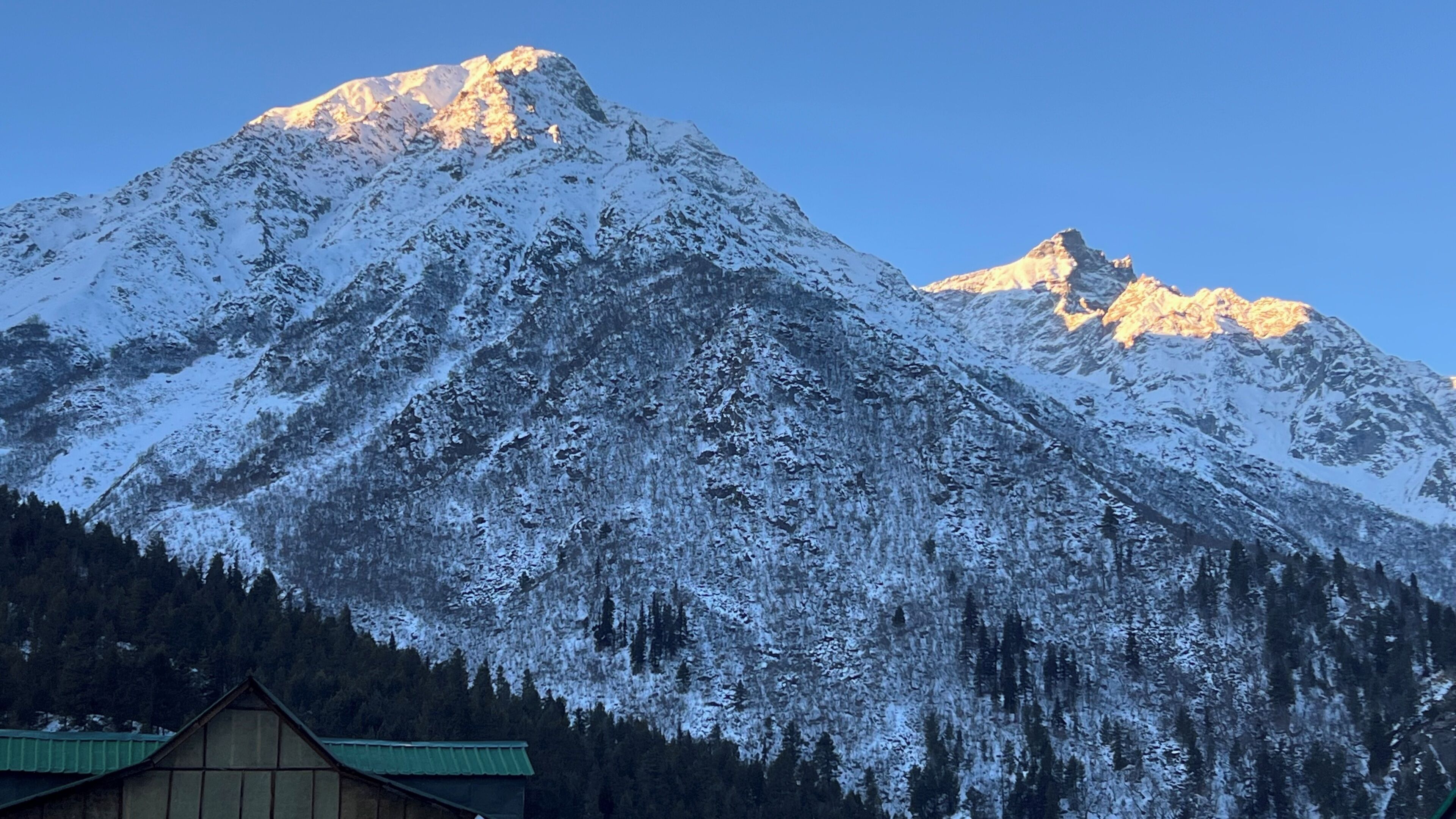 Una montaña cubierta de nieve con una cabaña en su base.
