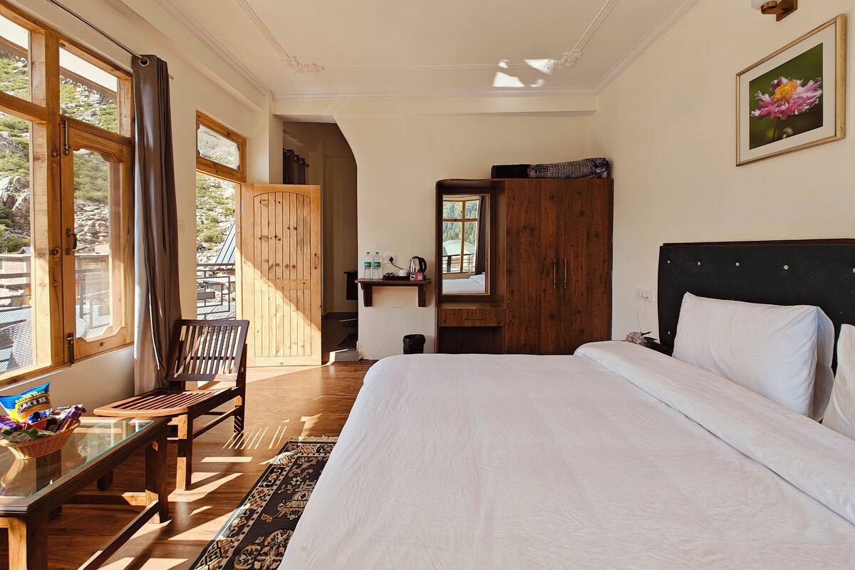 Quarto com cama grande, móveis de madeira, escrivaninha e guarda-roupa.