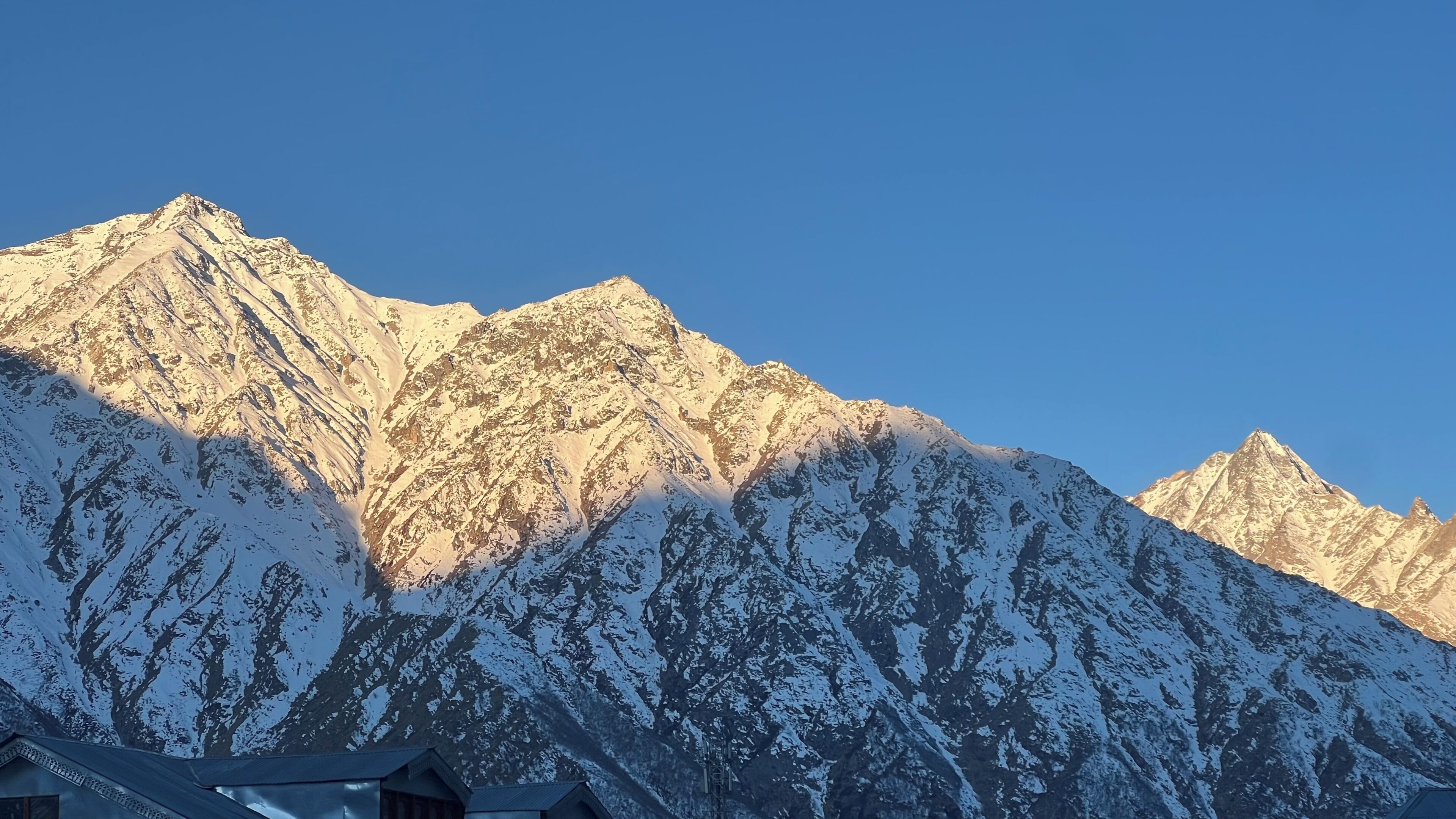 Une chaîne de montagnes aux sommets enneigés, sous un ciel dégagé.