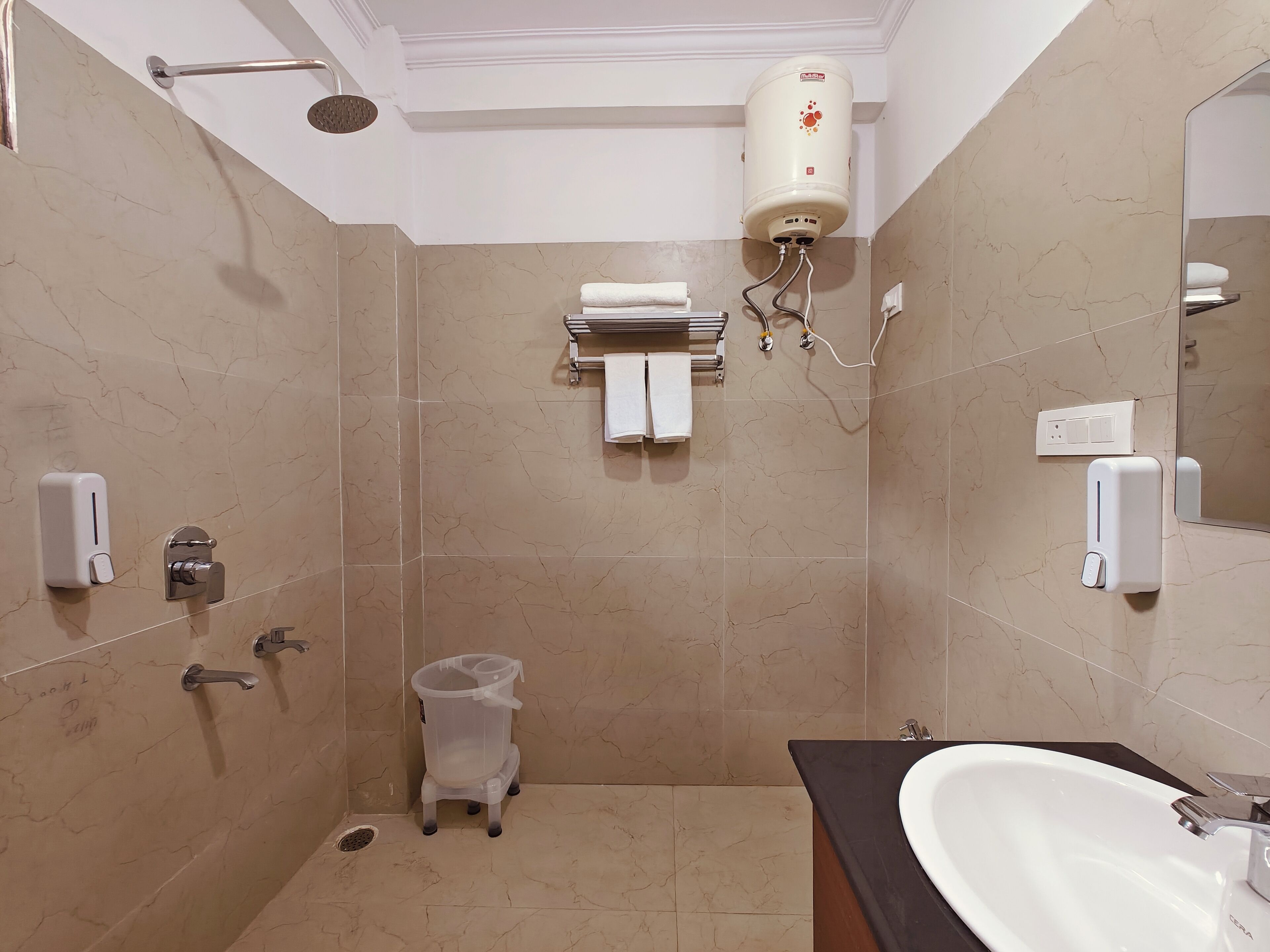 A bathroom with a shower, toilet, sink, towel rack, and a water heater.