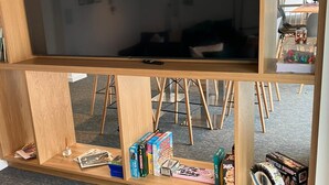 Ein Zimmer mit einem großen Spiegel, Holzböden mit verschiedenen Gegenständen und Blick auf einen Essbereich mit Stühlen und Tischen.