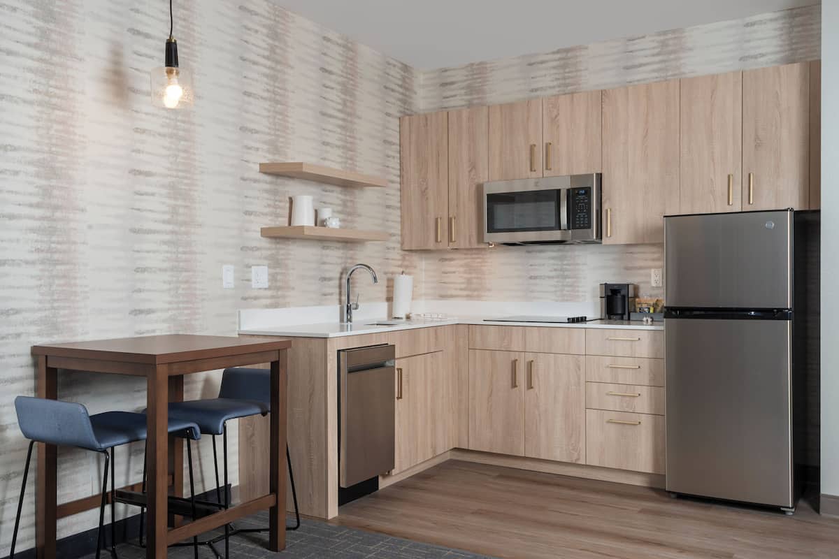 Eine moderne Küche mit Holzschränken, einem Edelstahlkühlschrank, einer Mikrowelle und einem Geschirrspüler.