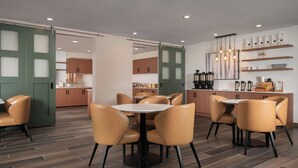 Una cocina moderna con armarios de madera, una isla central y un área de comedor con mesas y sillas redondas.
