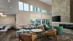 Un área de estar moderna con asientos, chimenea y ventanas amplias.