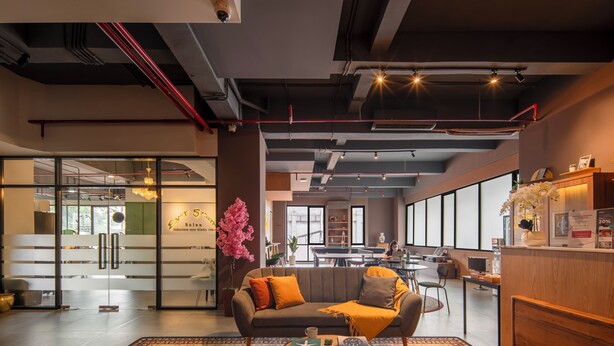 A modern hotel lobby with a sofa, coffee table, and a reception desk. - Cove Amartha (Jakarta)