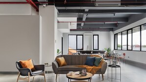 A modern living area with a sofa, two armchairs, a coffee table, and a dining table with chairs. - Cove Amartha (Jakarta)