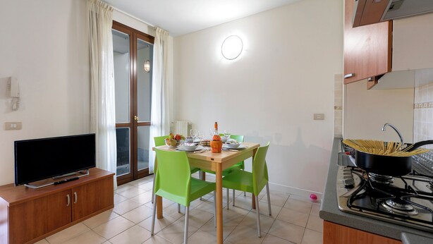 Une cuisine compacte comprenant une table à manger, des chaises, un téléviseur et une cuisinière.
