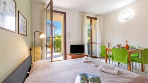 Une chambre d’hôtel équipée d’un lit, d’une télévision, d’une table à manger avec des chaises et offrant une vue sur l’extérieur.