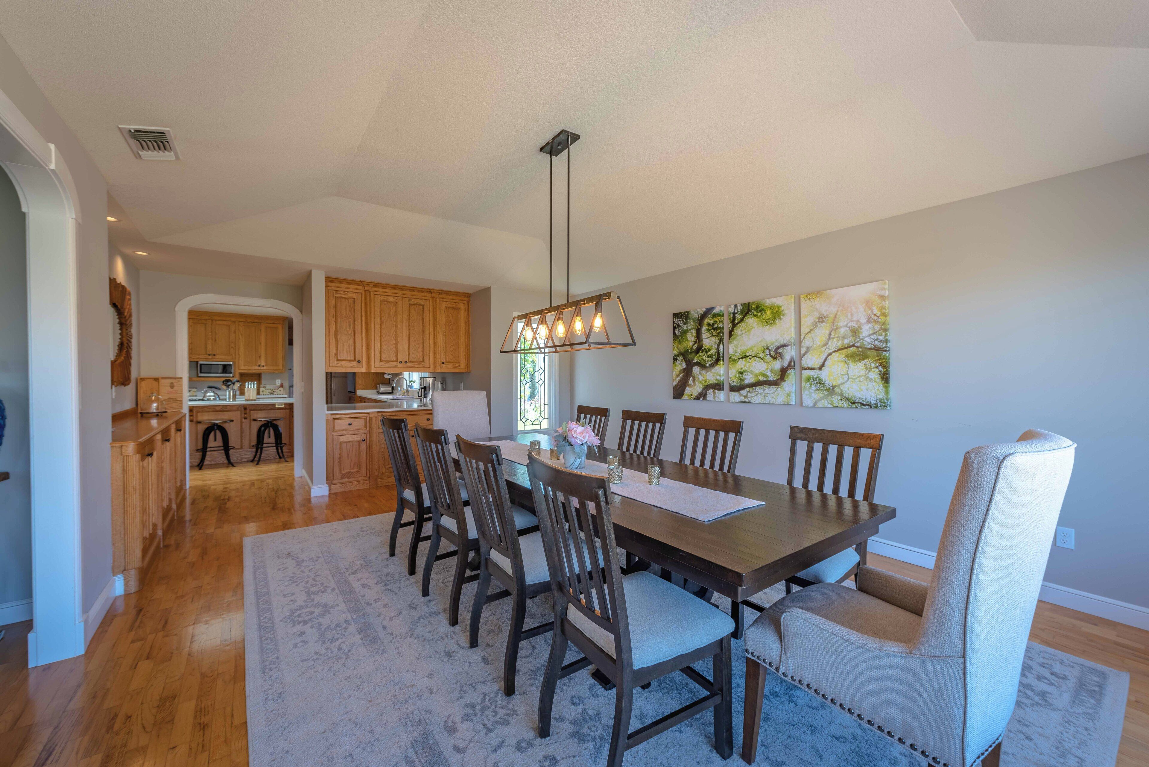 A dining area with a wooden table and chairs, a chandelier, and artwork on the wall.