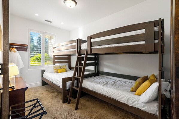 Habitación con literas, un escritorio con lámpara y una ventana con persianas.