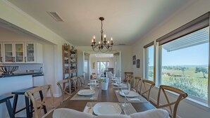 A dining room with a long table set for a meal, wooden chairs, and a chandelier. - Hidden Acre Vineyard (Paso Robles)