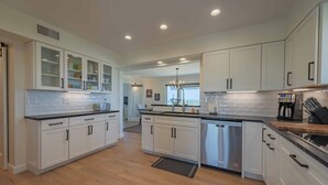 A modern kitchen with white cabinetry, a stainless steel dishwasher, and a black countertop. - Hidden Acre Vineyard (Paso Robles)