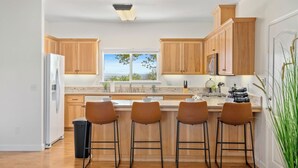 Una cocina moderna con armarios de madera, un ventanal grande y una barra con taburetes.