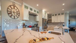 A modern kitchen with a marble island, stainless steel appliances, and a clock on the wall. - Bella Vita (Paso Robles)