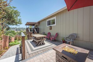 Un patio con mesa y sillas de madera, una parrilla y una pérgola.