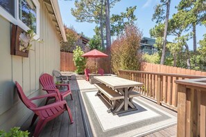 Una terraza con una mesa de picnic y sillas, rodeada por una valla de madera y árboles.