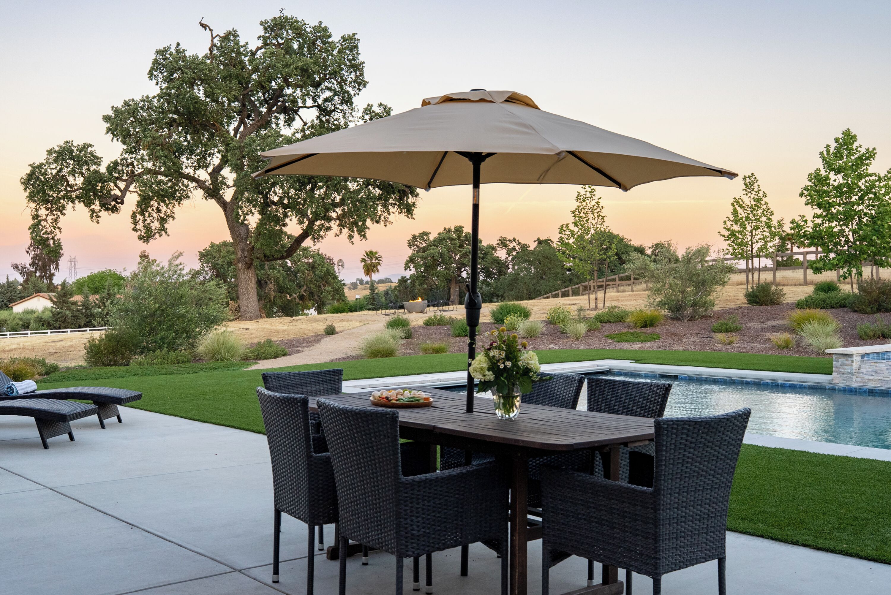 An outdoor patio with a dining table, chairs, and an umbrella.