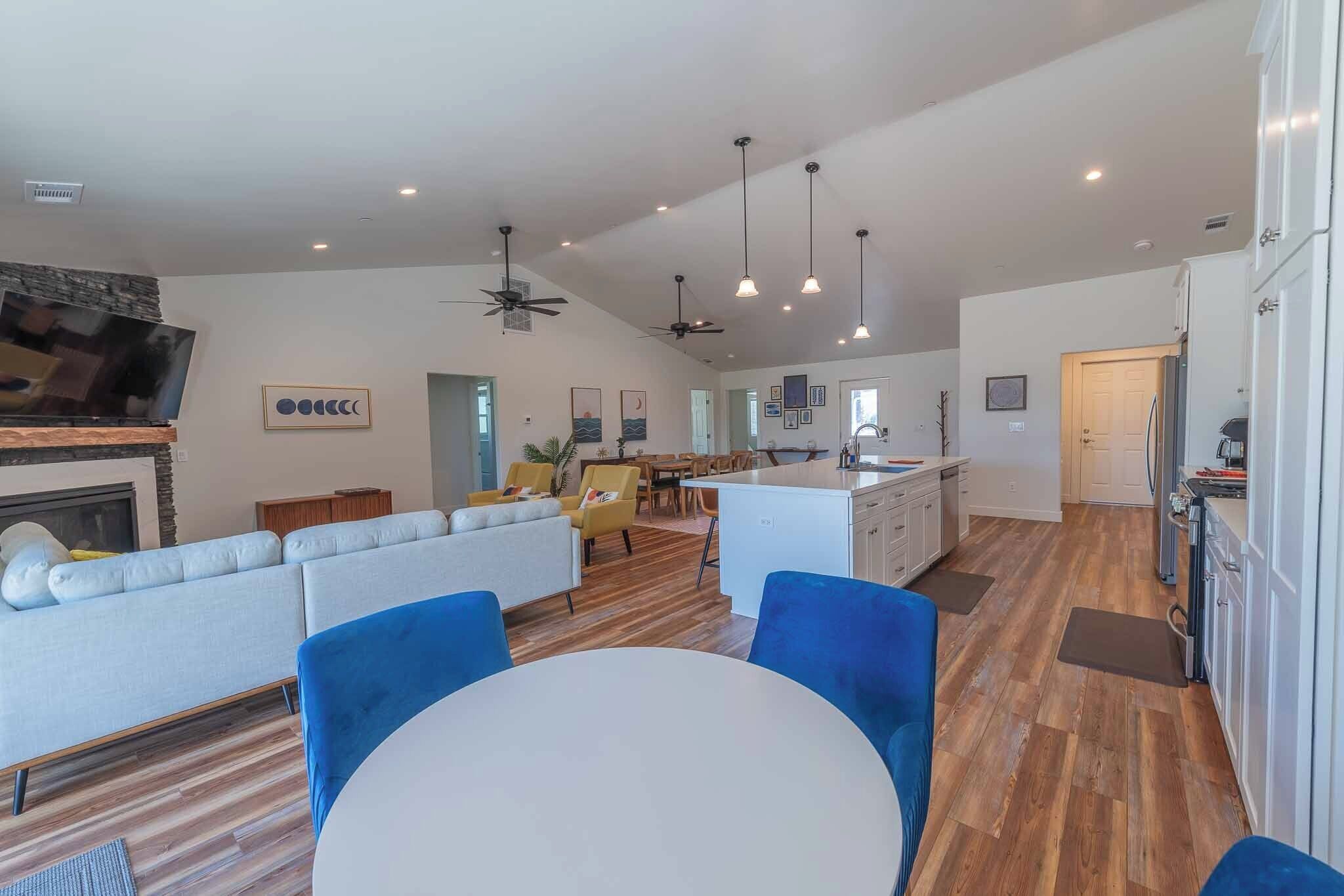 A spacious living area with a sofa, dining table, and chairs, a kitchen with cabinets and appliances, and a ceiling fan.
